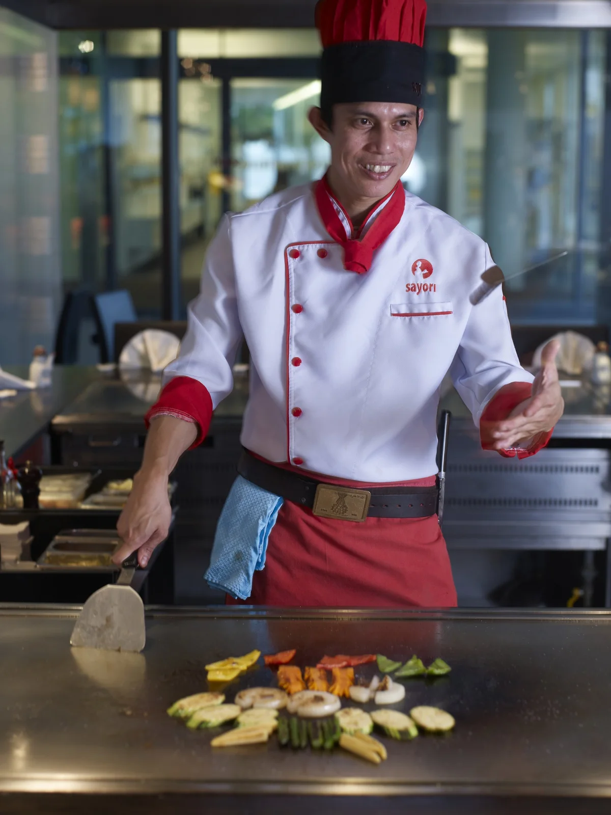 Koch bereitet Gemüse auf der Teppanyaki-Platte zu