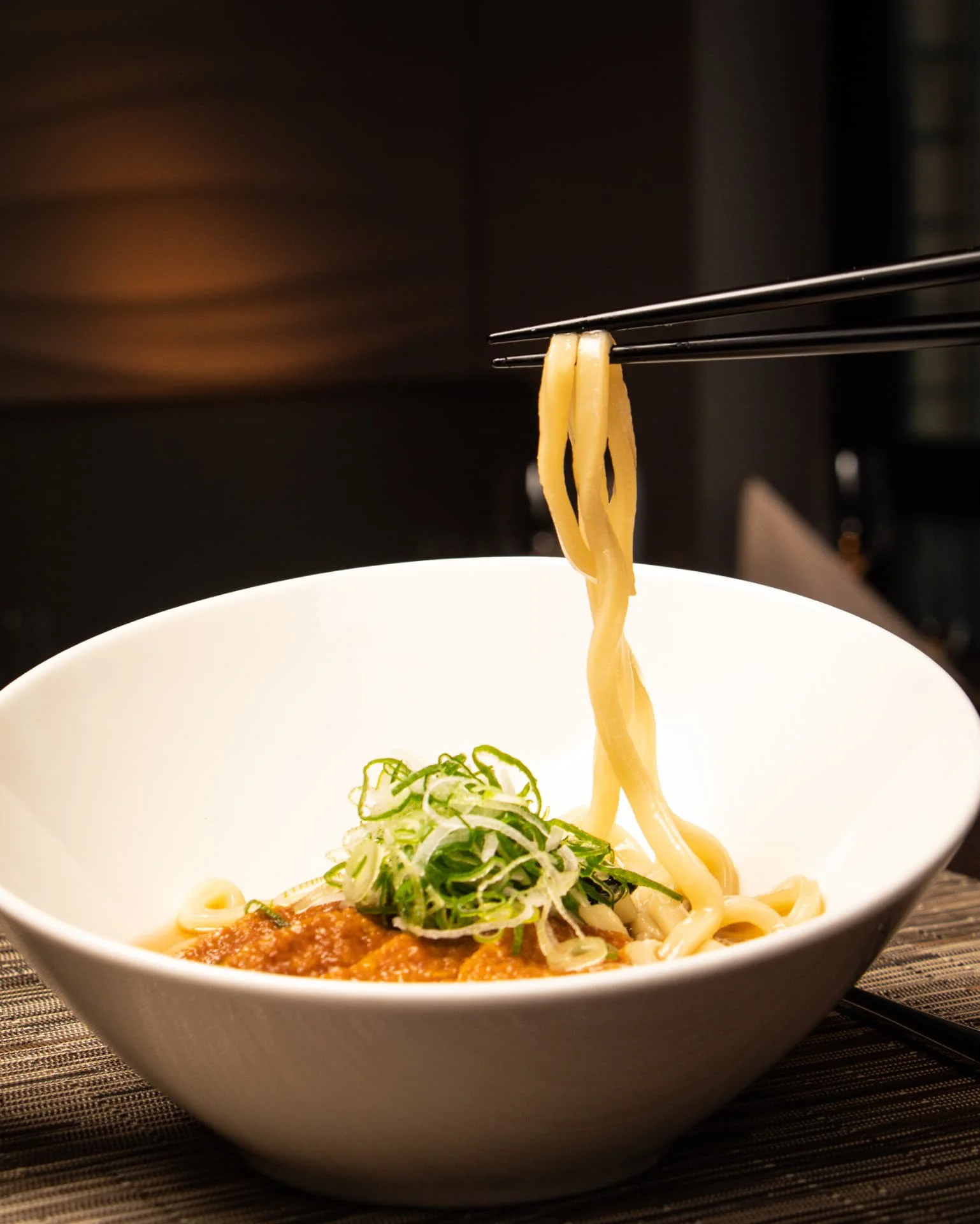 Udon-Nudeln werden mit Stäbchen aus der Schale gehoben